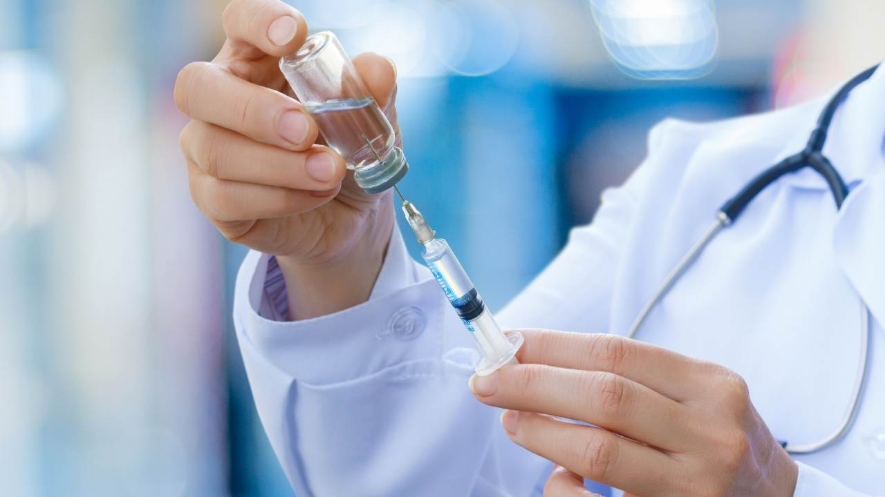 Médico preparando cerinha com vacina para ser administrada.