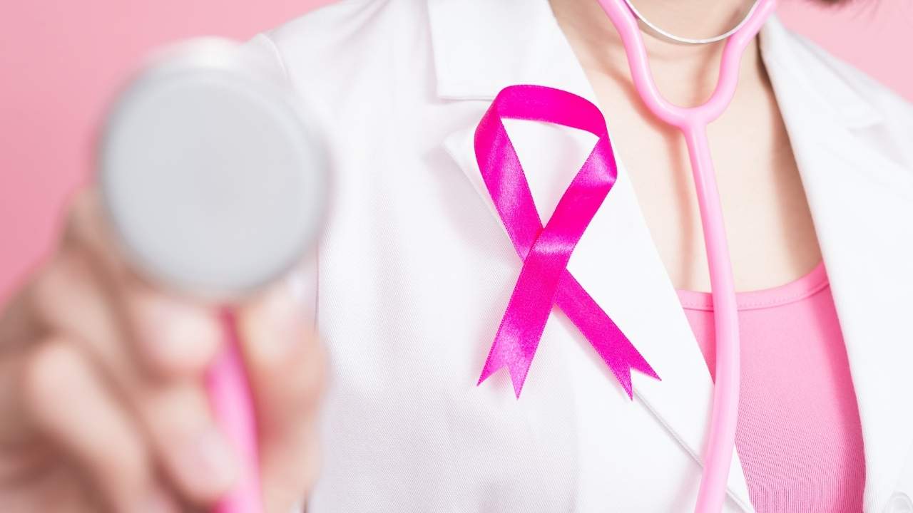 Médica com símbolo do outubro rosa alertando sobre o tratamento do câncer de mama.